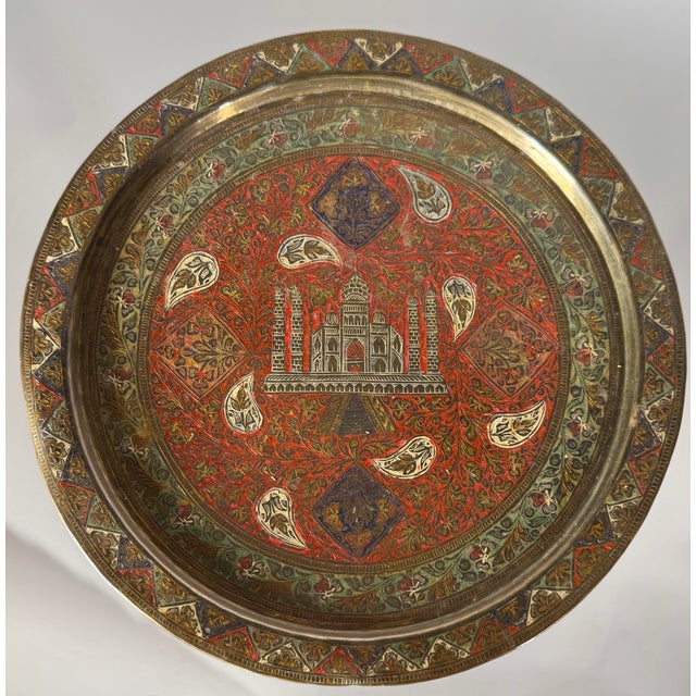 This striking vintage brass tray features an engraved architectural depiction of the Taj Mahal, surrounded by intricate...