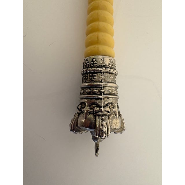 Vintage hand-held magnifying glass with an ornate, silver-toned handle decorated with detailed metalwork, a ribbed faux-...