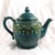This is an unmarked dark teal teapot that is a working teapot that has a music box in the base. I am not sure what song...