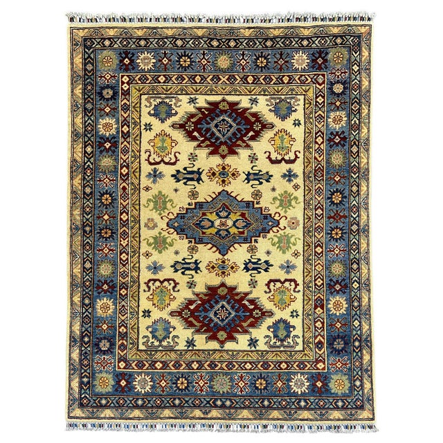 This Kazak-style wool area rug features three bold medallions on an ivory field, surrounded by geometric motifs in rust...