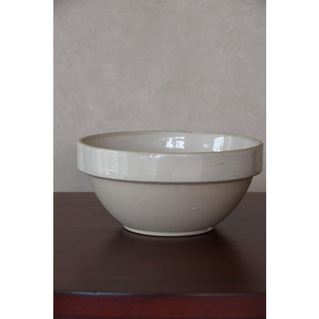 A traditional French ironstone bowl in a creamy off-white glaze, with a wide flat rim, slightly rounded body and footed...