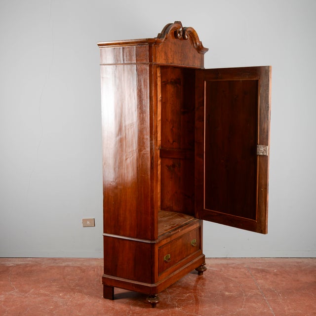 This impressive antique single-door wardrobe, dating back to the early 20th century, is a classic example of functional...