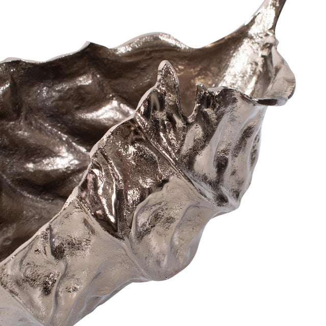 Crafted in the shape of a leaf and dipped in aged brass, this platter features dramatic edges, and its reflective surface...
