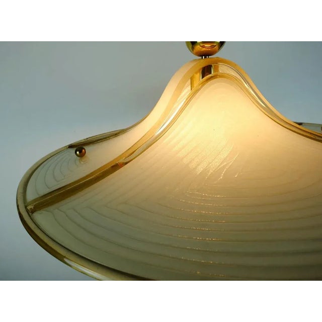 Impressive 70s hanging lamp made of eggshell -colored and transparent gold -colored acrylic and brass. Continuously...