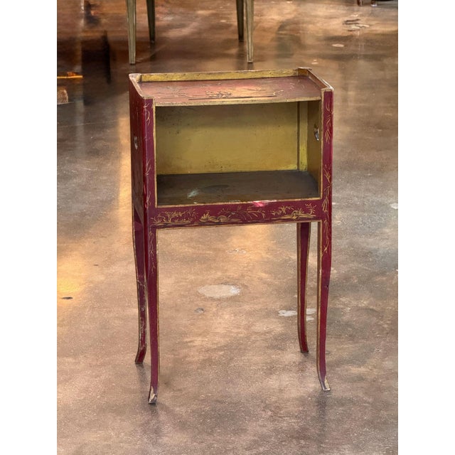 A slender side table of bedside form, decorated overall on a red ground with raised gilt chinoiserie. The galleried top...
