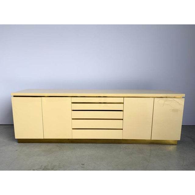 Luxurious seventies glamour sideboard by Jean claude Mahey consitsing of cream lacquer panels and brass. The use of...