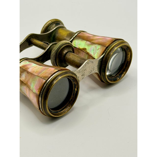 Elegant antique French opera glasses featuring luminous mother of pearl panels framed in richly patinated brass. A...