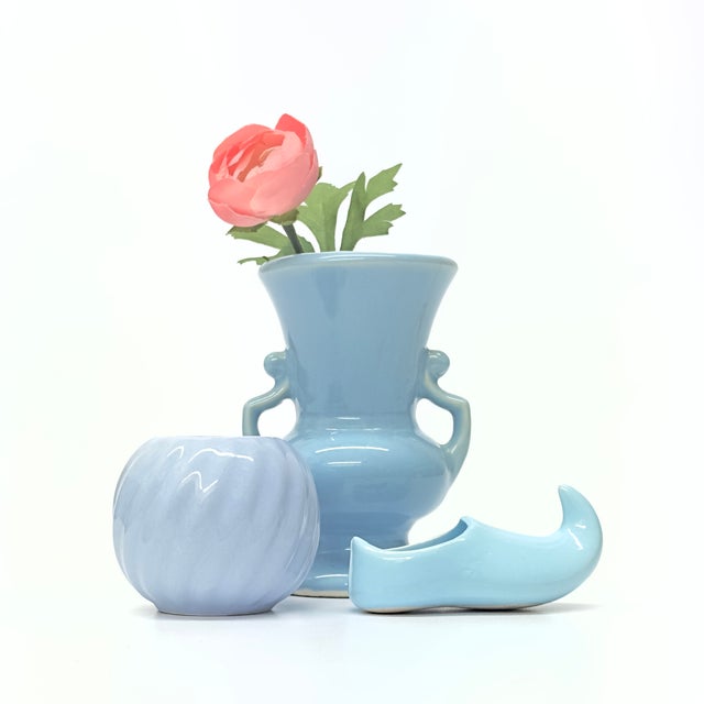 Mixed sky blue vessels, group of 3. This set of small mid-century ceramic vessels features a couple vases and a clog in a...