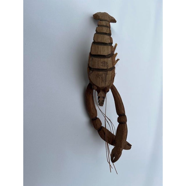 A single life size carved wood sculpture of a lobster.