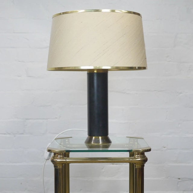 A 1950s brass and gold desk lamp. It features fabric shade with brass rim. This piece is attributed to the mentioned...