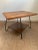 A vintage mid-century modern wood side table with two tiers and a swivel top. The table features hairpin style iron legs...