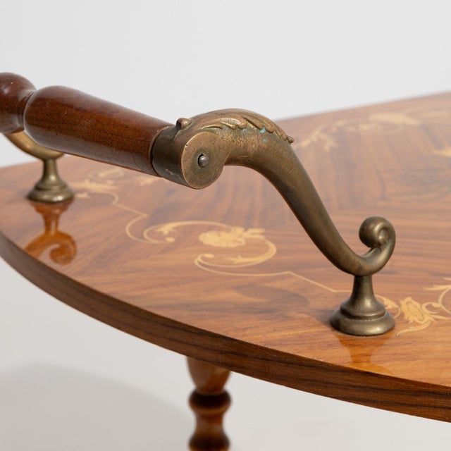 A bar cart whose dark mahogany with marquetry inlay, drop-leaf tiers, wheels gives it real character at first glance....