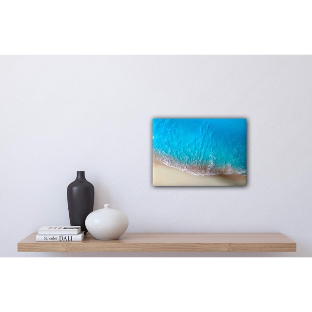 This artwork captures the serene beauty of a white sand beach, rendered in vibrant layers of resin that evoke the...