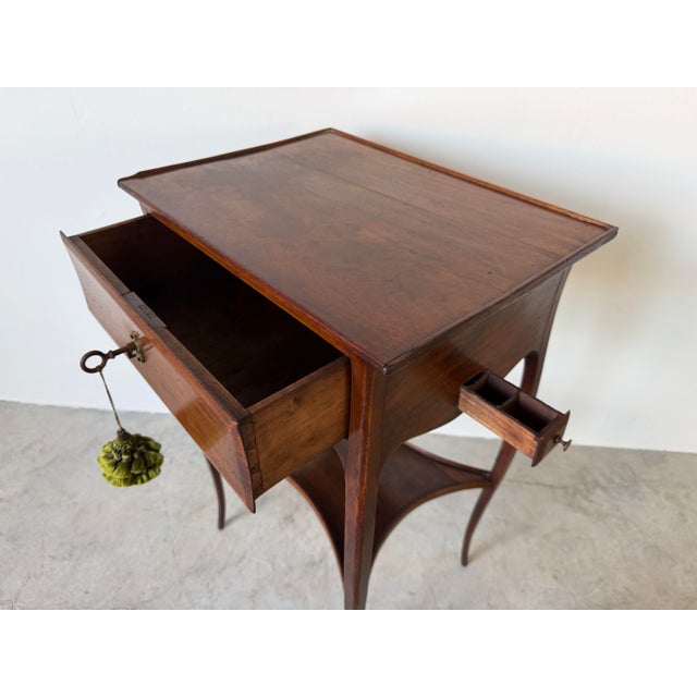 Charming antique French Louis XV-style lamp table or nightstand crafted in warm-toned wood, featuring elegant curved...