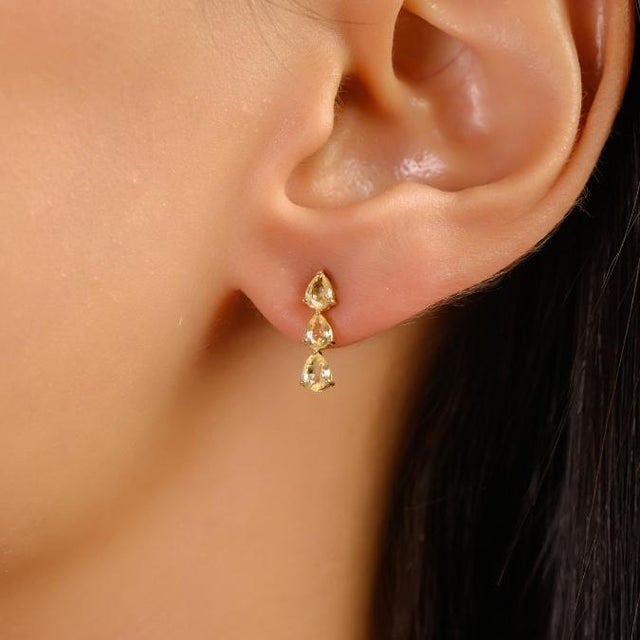 These elegant drop stud earrings feature six pear-cut yellow sapphires totaling approximately 1.16 carats, set in luminous...