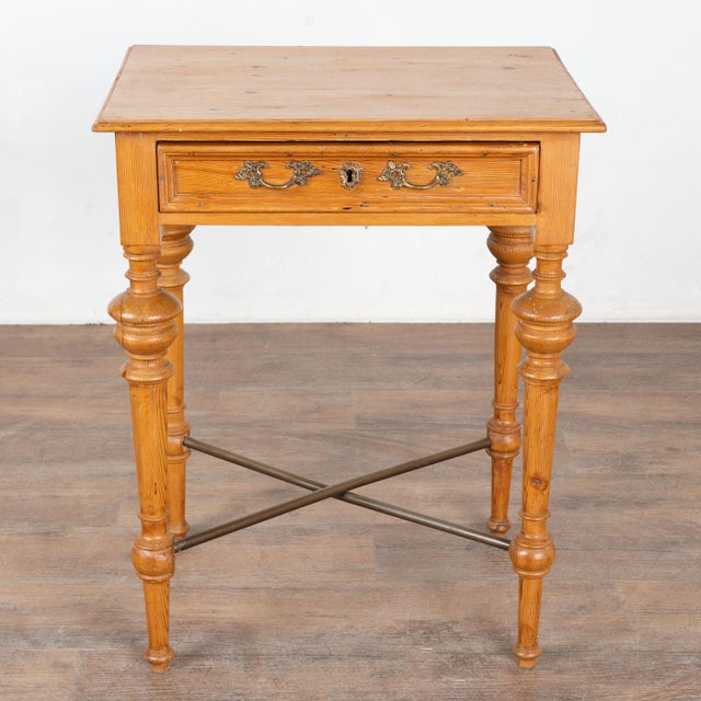Danish country pine side table with turned legs and small single drawer. Note the metal rods that cross the base, adding...