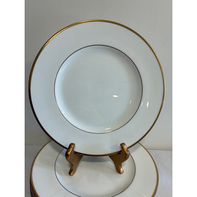 An elegant set of 12 Wedgwood bone china dinner plates in the "California" pattern, featuring a wide gold rim band and...