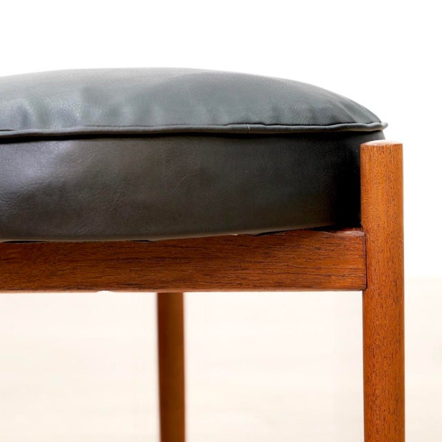 A well-crafted mid-century footstool featuring a solid teak frame and black vinyl cushion. Clean lines, warm teak tones,...