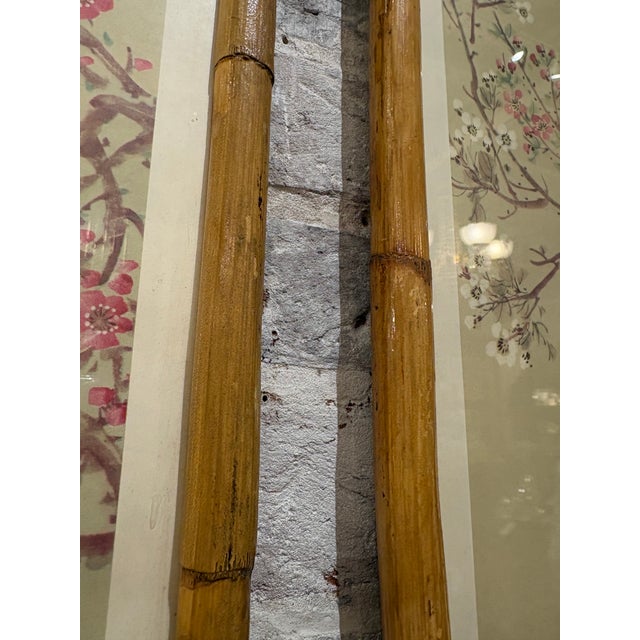 A striking pair of vintage Chinese prints mounted in natural bamboo frames, each capturing the delicate artistry of...