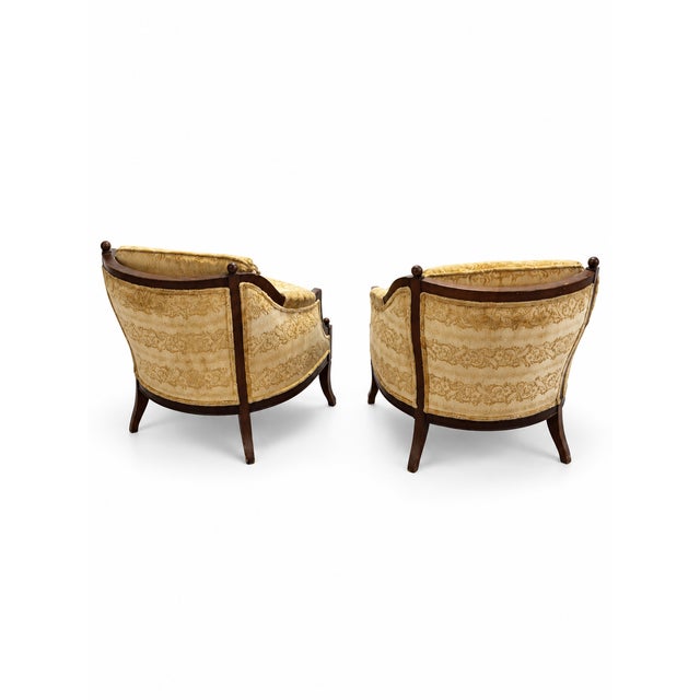 A distinctive pair of vintage barrel-back lounge chairs featuring gracefully curved exposed wood frames and richly...