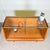 A charming cabinet that can serve as either a compact counter or a low display case. The unit stands on gold-colored legs...