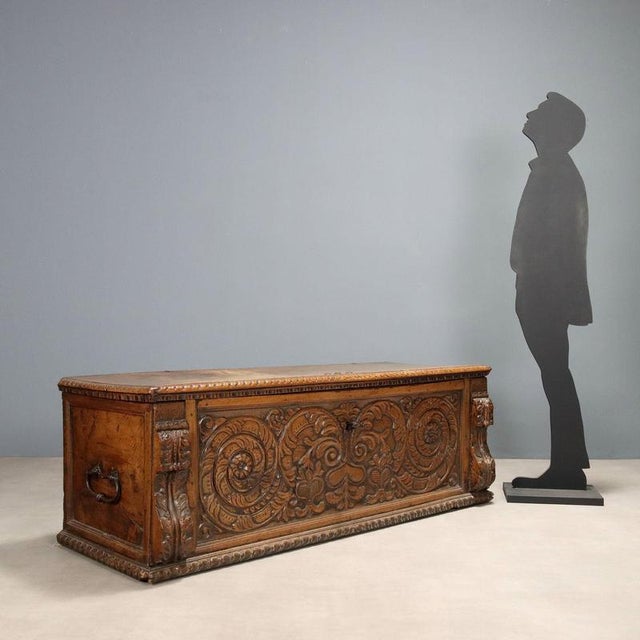 Walnut chest. Front with central panel carved with leafy motifs in a scroll-like pattern, projecting side uprights also...