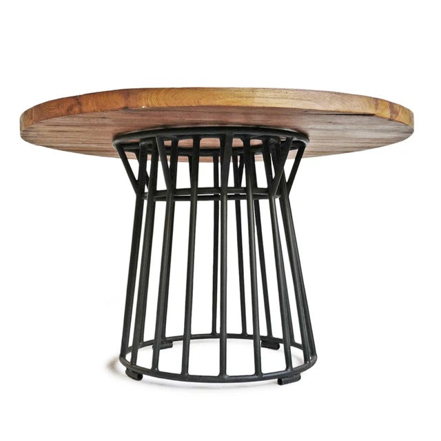 Handsome modern round teak wood dining table with black iron circular spindle base. Solid teak wood top is 2” thick with...