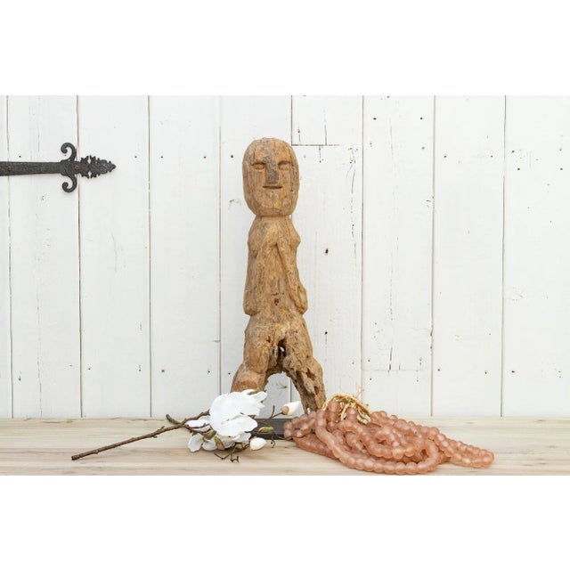 An antique Nepalese wooden statue from the Tharu people. This standing female figure from Nepal is hand-carved from wood...