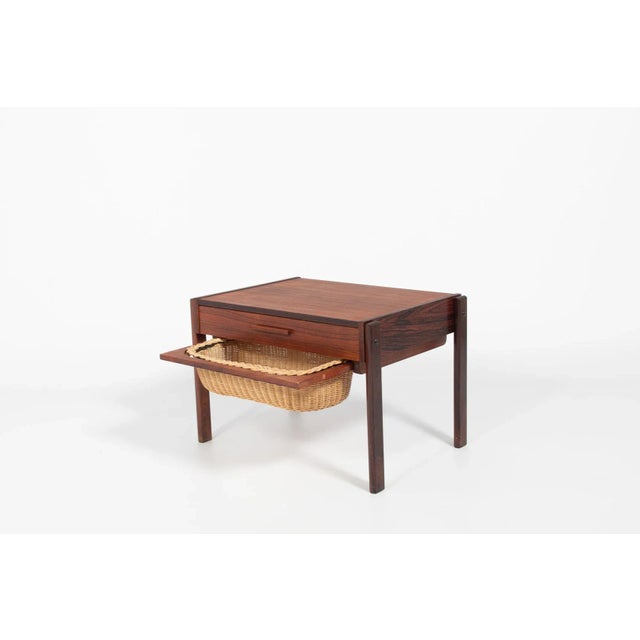 Side table/storage table in rosewood veneer with the wicker basket under. It has a drawer with small storage compartments....
