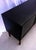 Large black sideboard with three doors, one of which opens to reveal three drawers. Solid teak legs. The two doors lock.