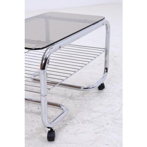 Beautiful vintage bar table with a chrome frame and glass top in a clean, light 70s style. Two levels on casters interlock...