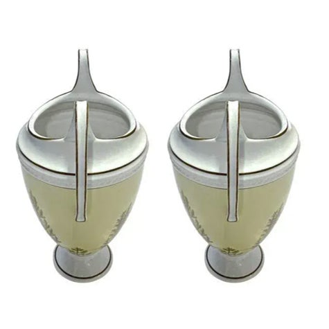 An elegant pair of vintage porcelain urns by Global Views, featuring beautifully exaggerated looping handles and delicate...