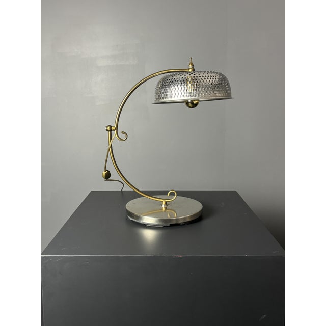 A sculptural brass table lamp from the 1970s, France or Belgium, combining a curved brass S-arm with a brushed-steel base...