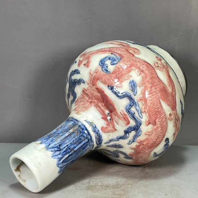 An elegant Chinese "tianqiuping" globe vase in the classic blue-and-copper-red style. The white-glazed body features a...