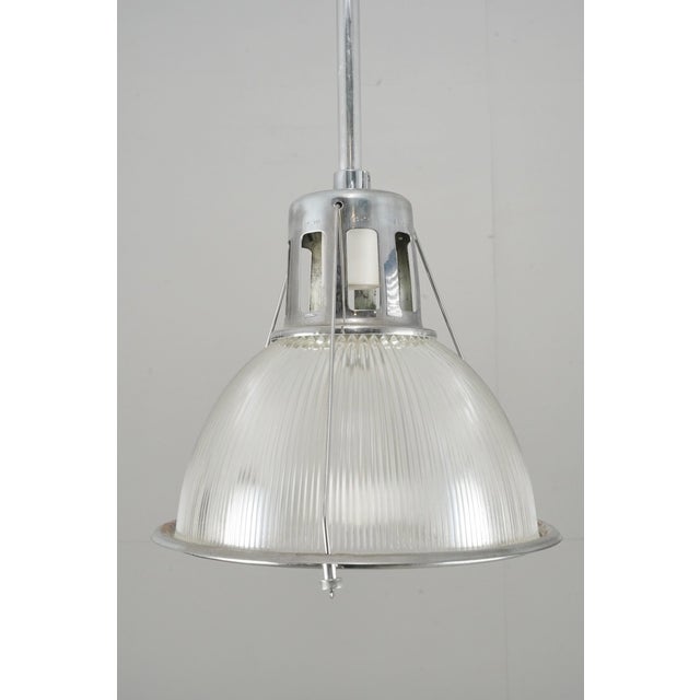 Industrial style pendant light with a chrome finished steel frame and Holophane clear glass shade. This requires one...