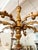This gold wooden chandelier has eight scrolling carved arms, each fitted with a candle. This chandelier is not wired.