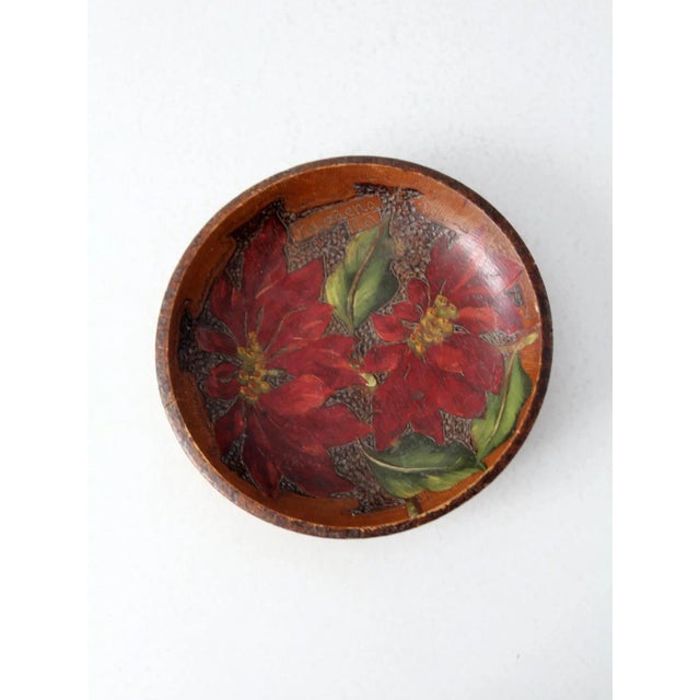 This is a mid 20th century vintage decorative bowl. The wood pyrography bowl features a poinsettia design with red, green,...