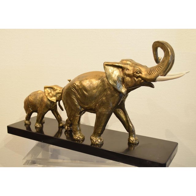 Elephant and his little one in regula with golden patina on black marble base signed Rochard. In very good condition with...