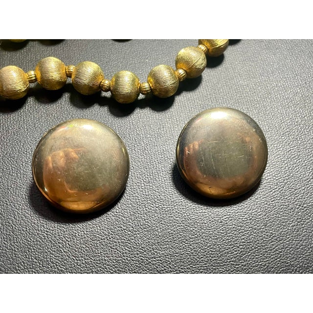 The standard spherical beads feature a heavy fine-line brushed or satin finish etched directly into the gold-tone metal....