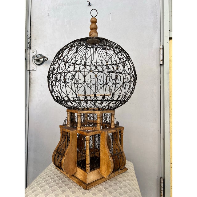 This is an ornamental Victorian-style bird cage featuring a "balloon" shape made from wrought iron and wood. brass...