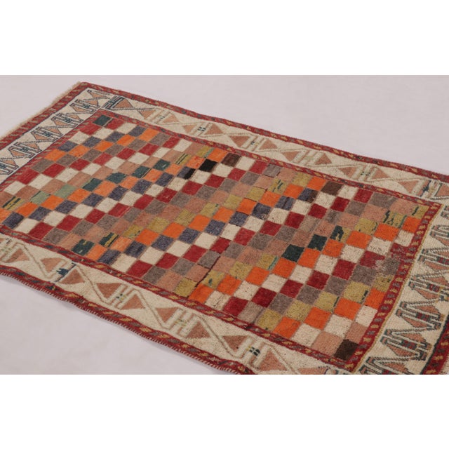 Hand-knotted in wool circa 1950-1960, this 3x5 vintage Persian Gabbeh rug is a vibrant celebration of tribal geometry. A...