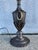 Neoclassical style urn-form steel lamp with brass oval rings on the sides and repousse acanthus leaf decoration. The round...