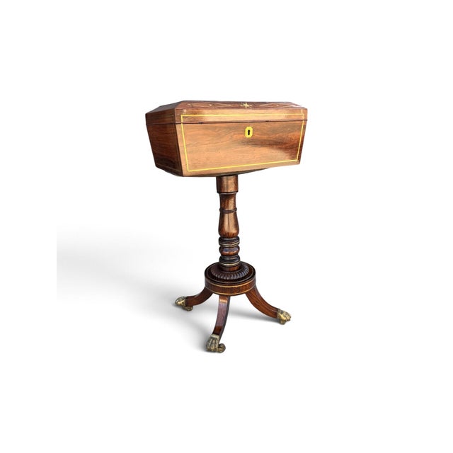 A fine English Regency tea poy crafted in richly figured rosewood with brass inlay and mounts. The hinged caddy opens to...