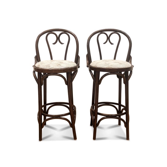 A pair of Thonet bentwood bar stools with the sweetheart design. The vintage stools have a newly upholstered cushion in a...