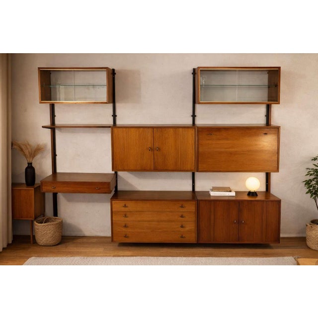 An elegant 1960s wall-mounted bookcase in teak veneer, enhanced by discreet brass handles. A warm and inviting design that...