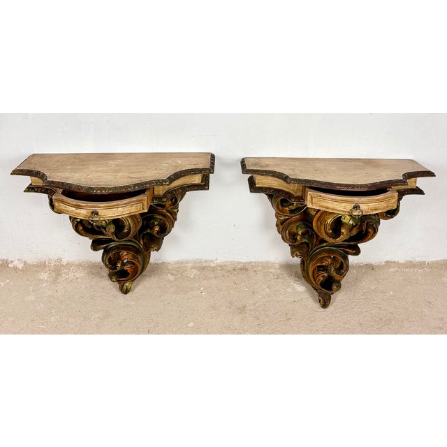 Elegant pair of Italian wall-mounted pedestals featuring finely carved polychromed supports with flowing acanthus...