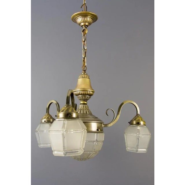 Elegant French Art Deco chandelier from the 1920s with three brass arms each with frosted glass shade and porcelain socket...