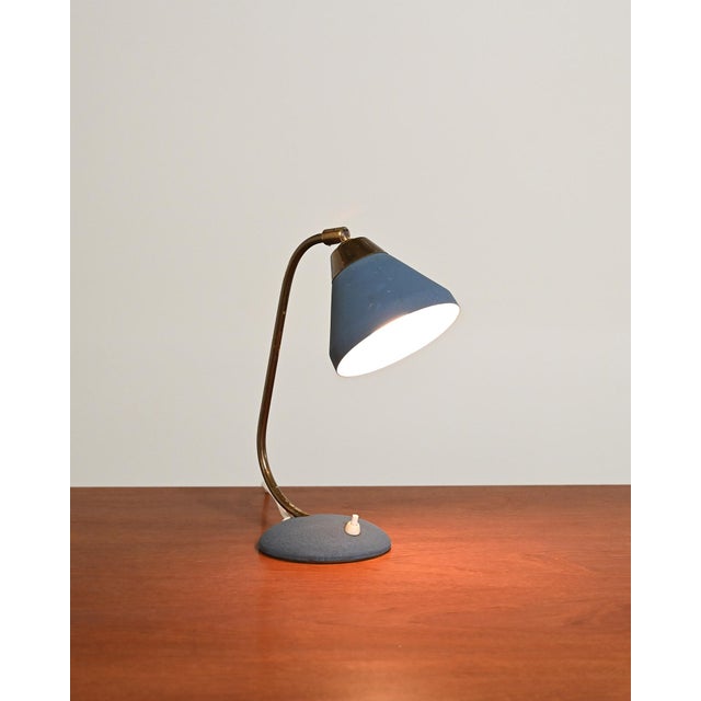 Blue painted metal frame with curved brass stem and adjustable conical diffuser. Ewå branding and "made in sweden" stamped...