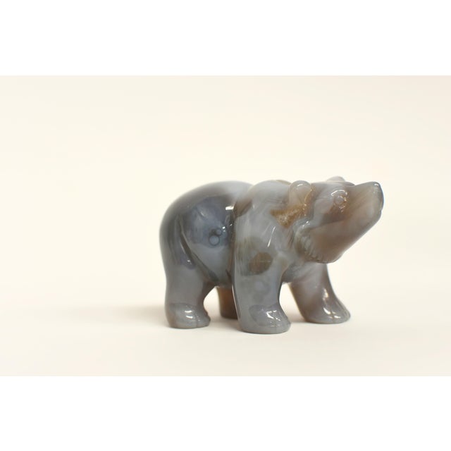 A hand-carved figurine of a walking bear, meticulously fashioned from a single piece of high-quality natural agate. This...