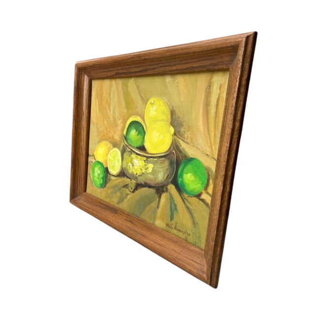 A dated, signed still life of lemons and limes, set in a simple oak, medium-brown toned, smooth wood frame. A footed...